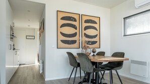 Un comedor con una mesa redonda de madera, cuatro sillas grises y dos grandes cuadros abstractos en la pared.