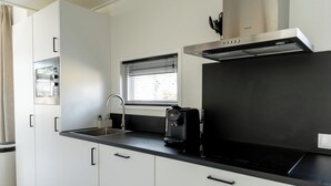 Una cocina moderna con un lavamanos de acero inoxidable, una cafetera y un ventanal con persianas.