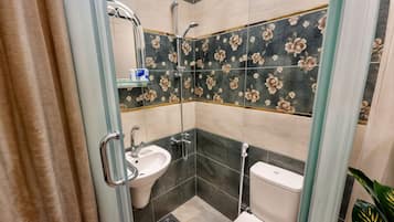 Un baño con cabina de ducha de vidrio, lavabo e inodoro.