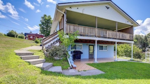 Une maison à deux étages dotée d’un balcon, d’un porche à l’avant et d’un petit jardin devant, avec des marches menant à l’entrée.