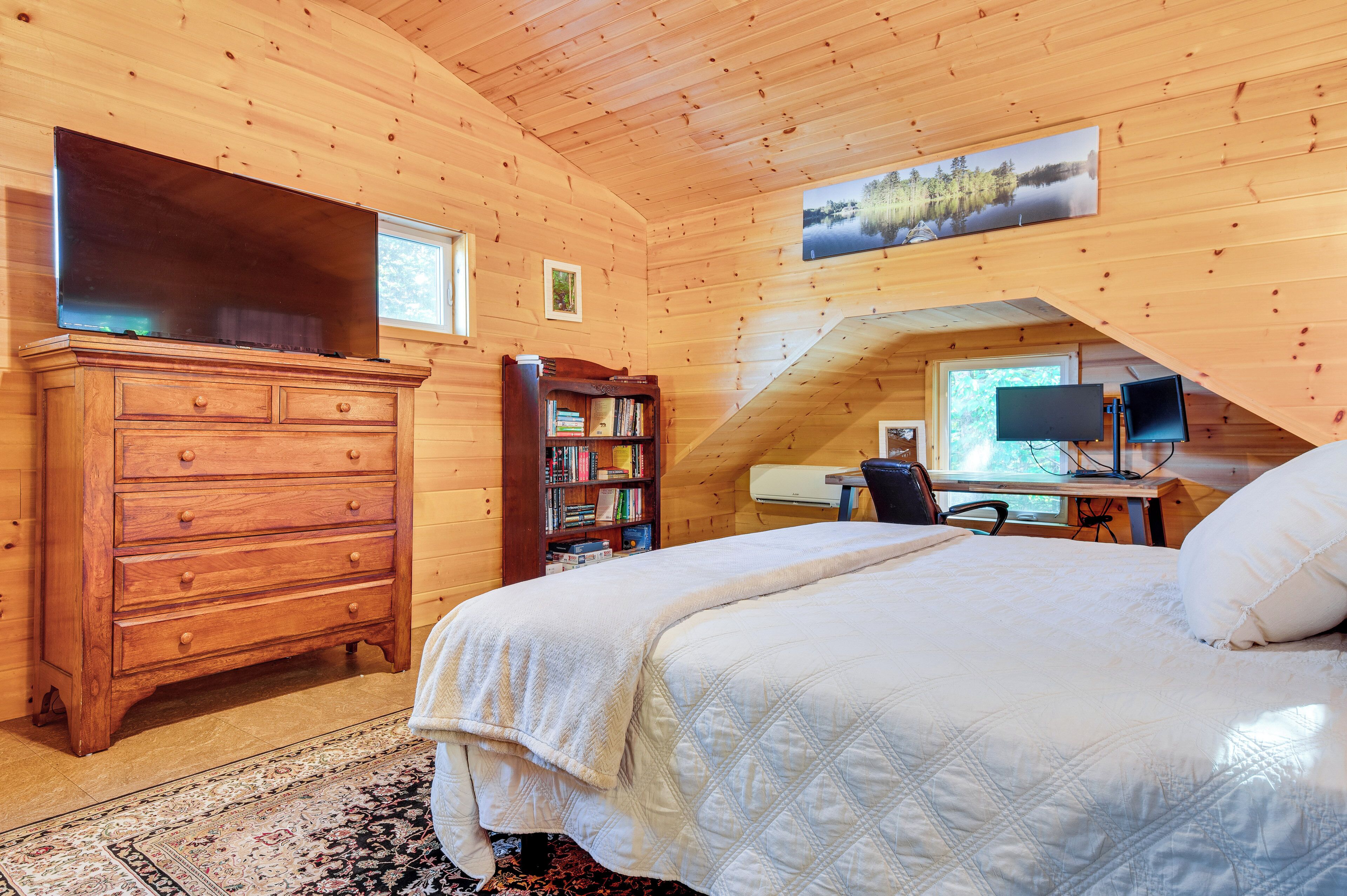 Une chambre confortable avec un grand lit, une commode, une bibliothèque, un bureau avec un ordinateur et une télévision.