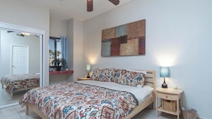 Ein Schlafzimmer mit einem großen Bett, zwei Nachttischen, einem Deckenventilator und einem Fenster mit Vorhängen.