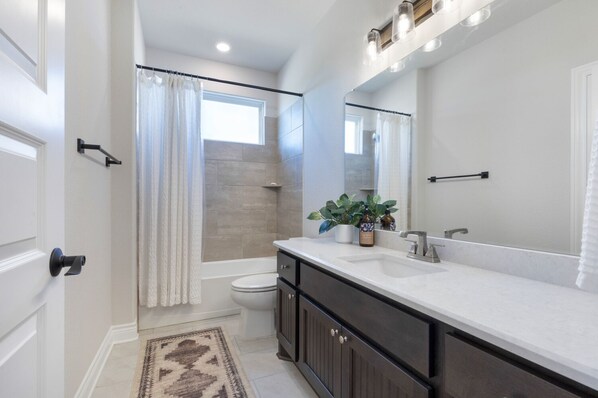 A modern bathroom with a shower, toilet, and sink.