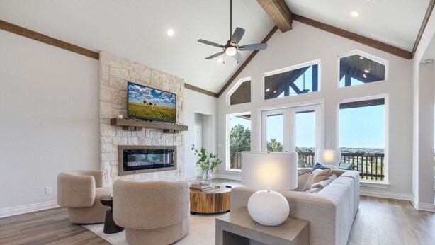 Un salón amplio con chimenea de piedra, un televisor grande y una zona de estar confortable con vistas al exterior.