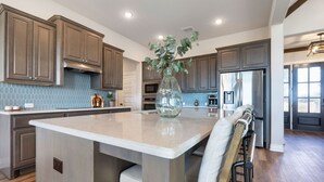 Una cocina moderna con una isla grande, armarios de madera oscura y un salpicadero con baldosas hexagonales.