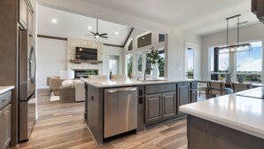 Una cocina moderna con una isla grande, electrodomésticos integrados y un salpicadero de piedra.