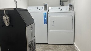 Une buanderie équipée d’un lave-linge à chargement frontal, d’un sèche-linge à chargement par le haut et d’étagères au-dessus pour ranger les produits de nettoyage.