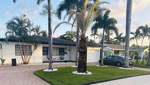 A modern house with a garage, a driveway, and a lawn with palm trees. - Wilton Manors Guesthouse #6 (Wilton Manors)