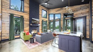 A spacious living area with a fireplace, a sofa, and a dining area with a bar. - Couples Retreat: Sauna, Massage Chairs, Hot Tub (Broken Bow)