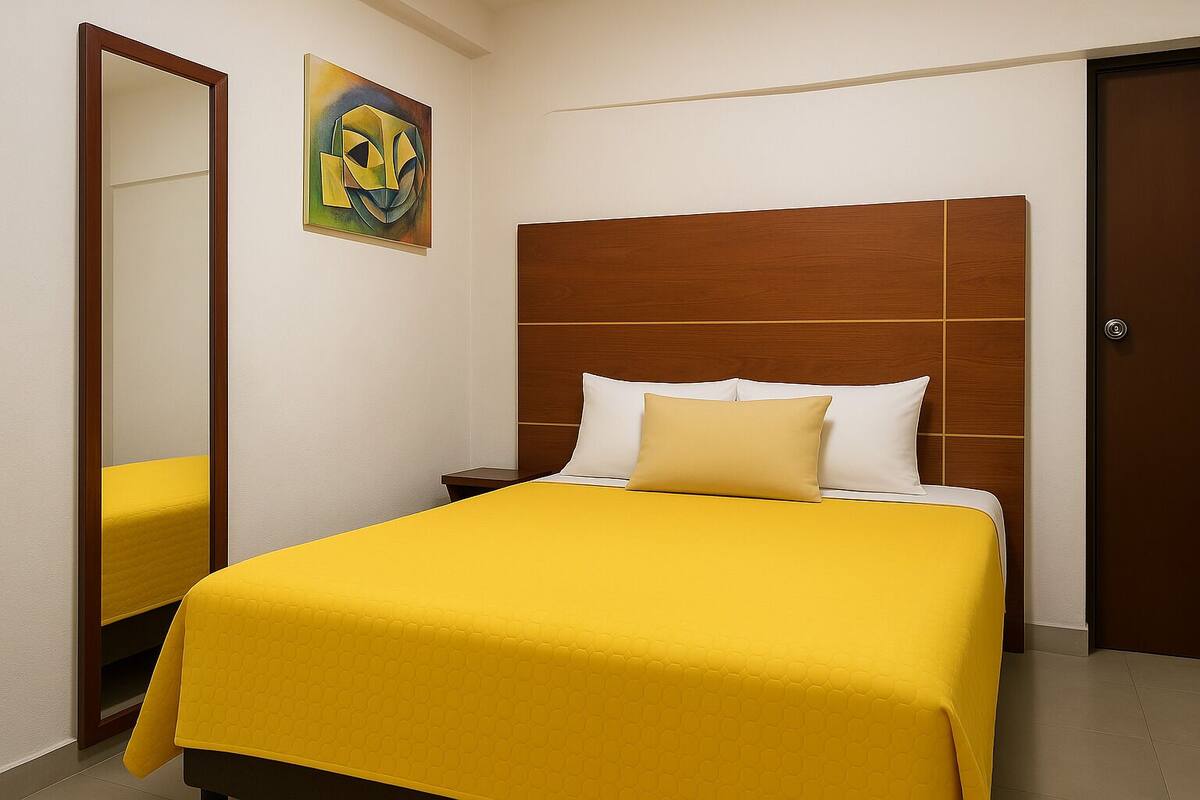 Une chambre d’hôtel avec un grand lit, une tête de lit en bois, une table de chevet et un miroir.