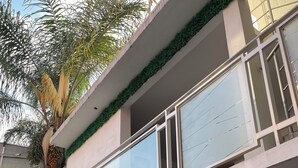 A building with a glass facade, a balcony with a railing, and a palm tree in front. - Hotel Galería & Boutique (Mexico City)
