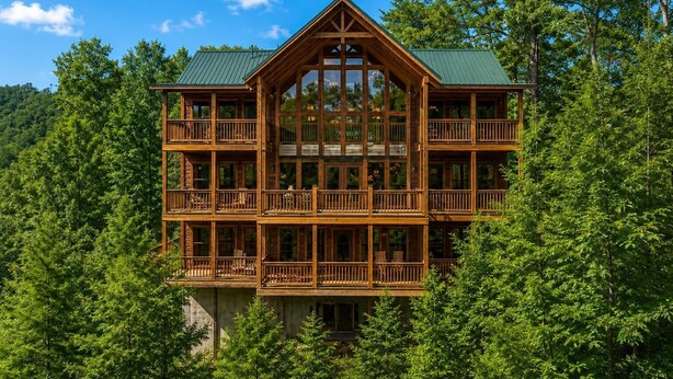 A multi-story log cabin with balconies, surrounded by dense forest.