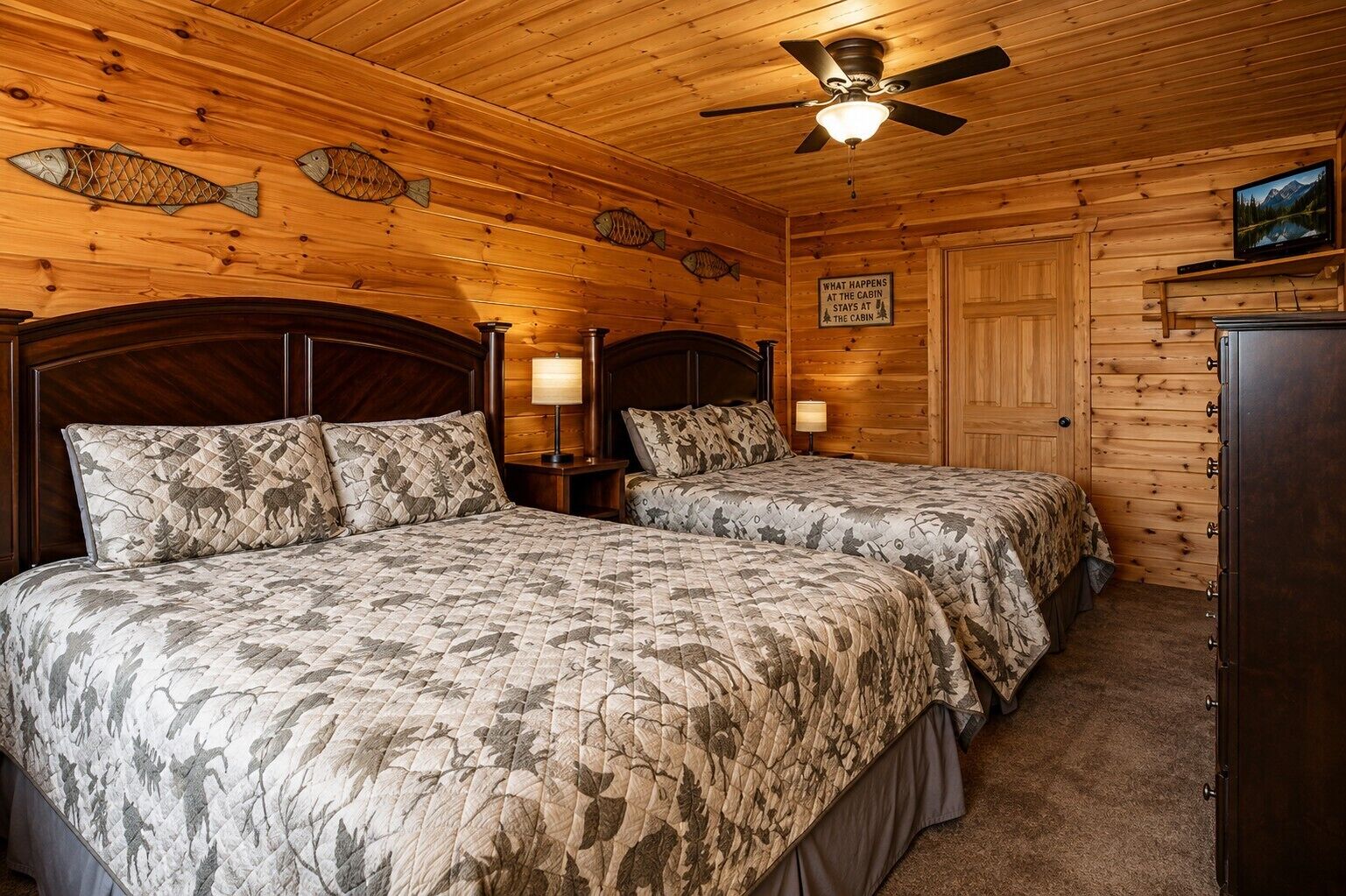 A cabin-style bedroom with two beds, wooden walls, a ceiling fan, and a sign on the wall.