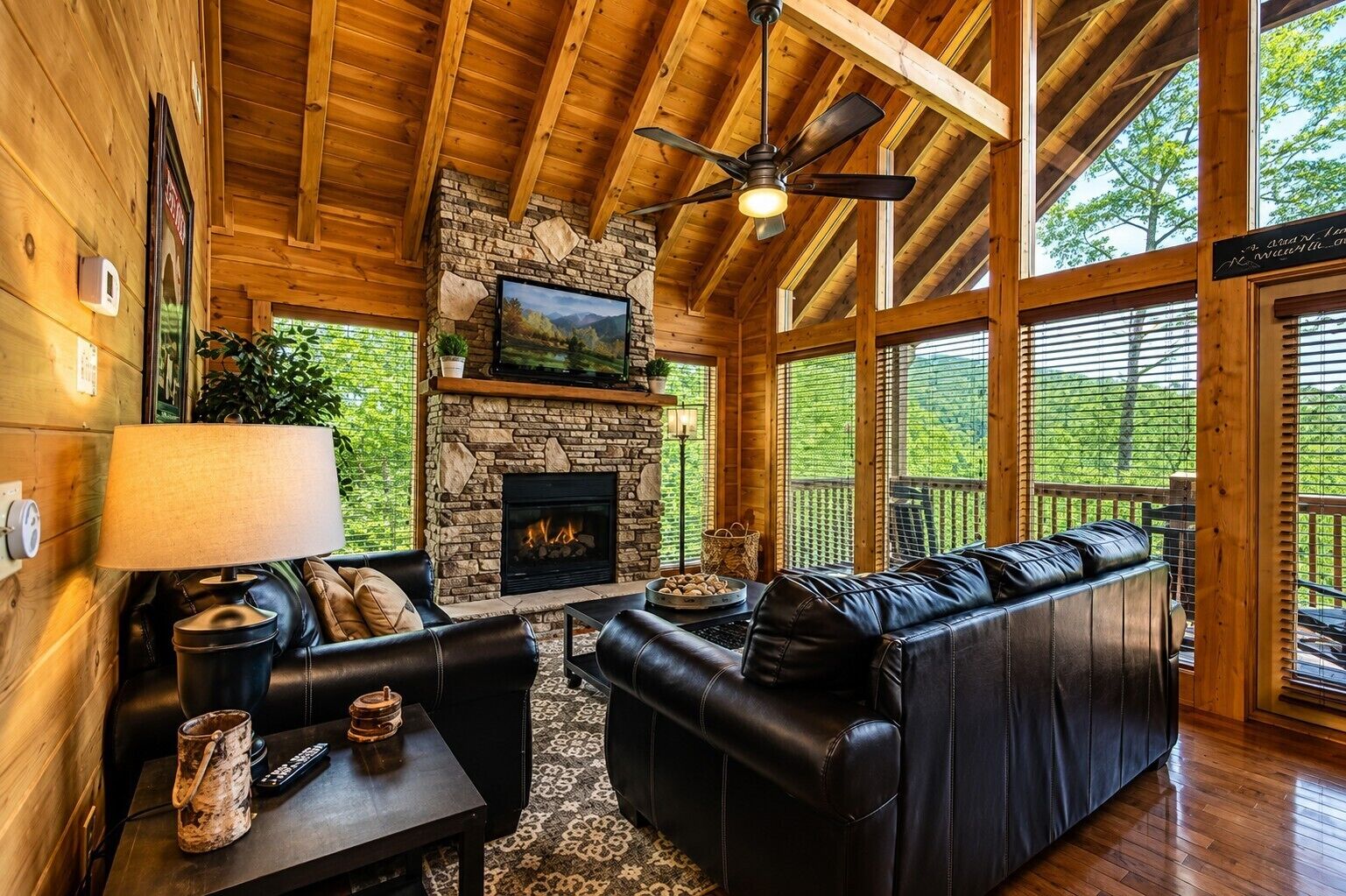 A log cabin interior with a stone fireplace, leather seating, and a television.