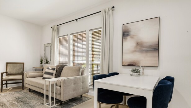 A modern living room with a sofa, a dining table with chairs, and large windows with blinds. - Orchid: Studio Apt, 4 Minute Walk to A&M (College Station)
