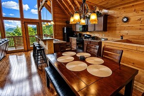 A wooden interior with a dining table, chairs, and a kitchen area.