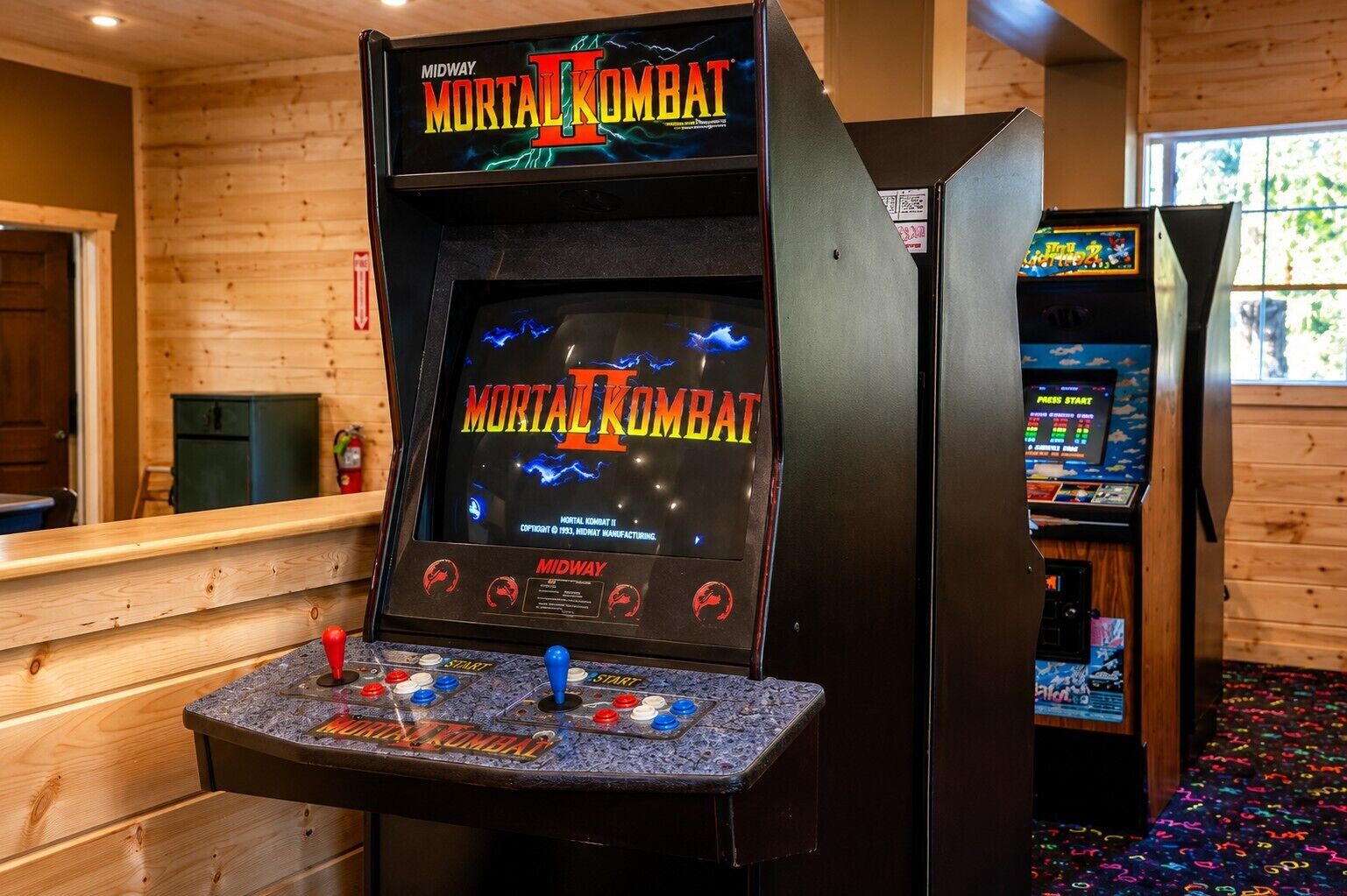 A Midway arcade with Mortal Kombat II game machines, wooden walls, and a counter area.