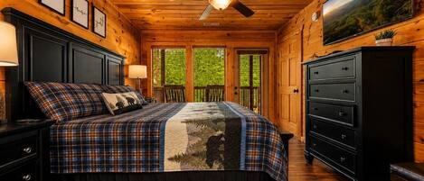 A bedroom with a bed, dresser, nightstand, and a ceiling fan.