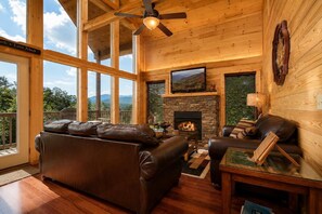 Una sala de estar acogedora con chimenea, sofá de cuero y televisor.
