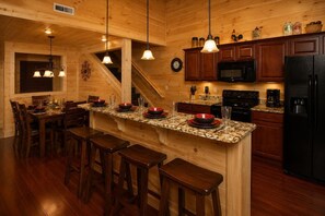 A wooden interior with a kitchen island, bar stools, and a dining area.