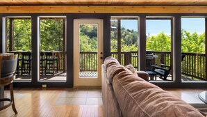 Un plafond en bois, une porte-fenêtre coulissante, un canapé marron et une terrasse avec des meubles d’extérieur.
