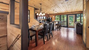 Un intérieur en bois comprenant un coin repas, une cuisine et de grandes fenêtres.