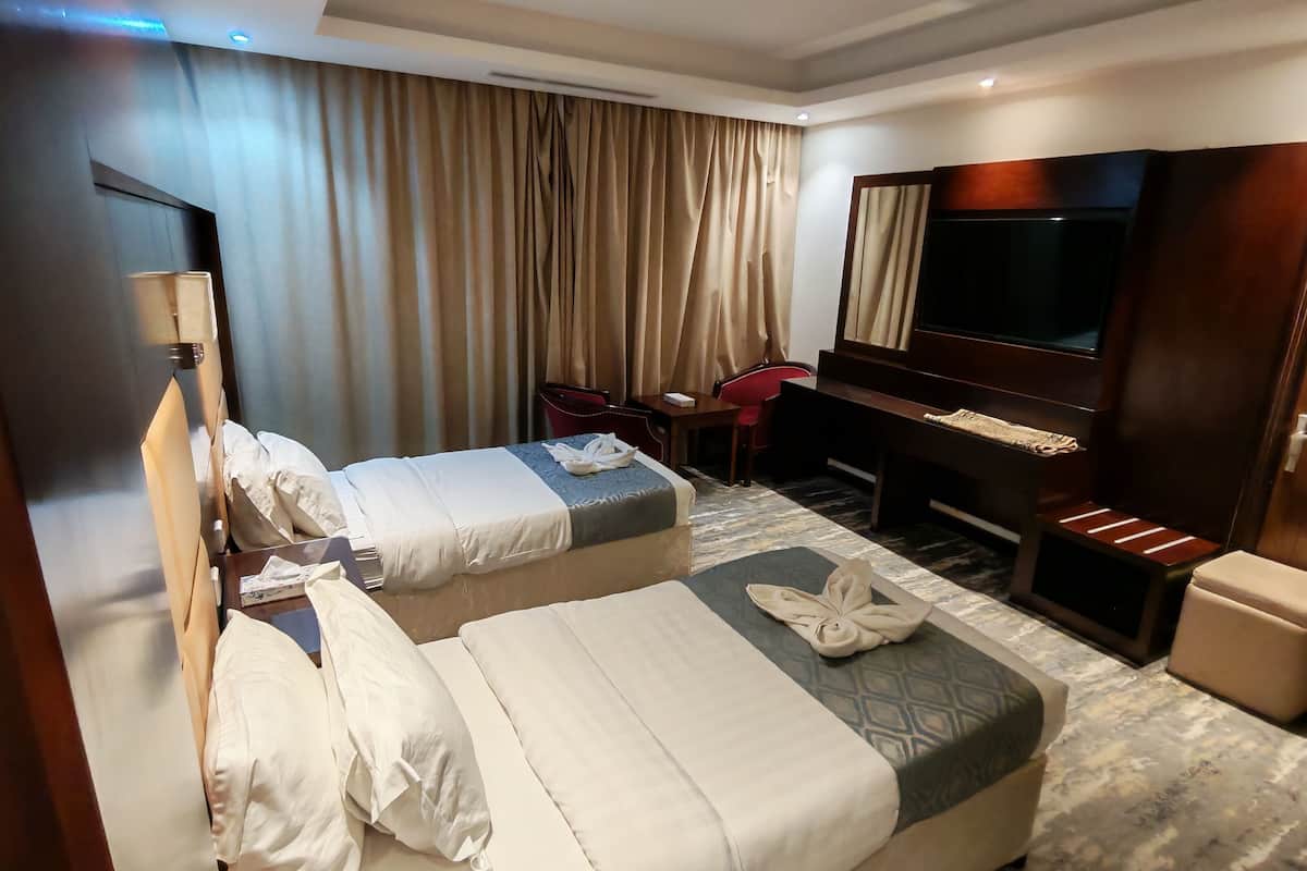 Une chambre d’hôtel avec deux lits, une télévision, un bureau, une chaise et une salle de bain.