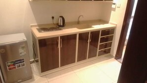 A compact kitchen with a refrigerator, a kettle, and a sink. - Arjan Almutamyezah serviced apartments (Jeddah)