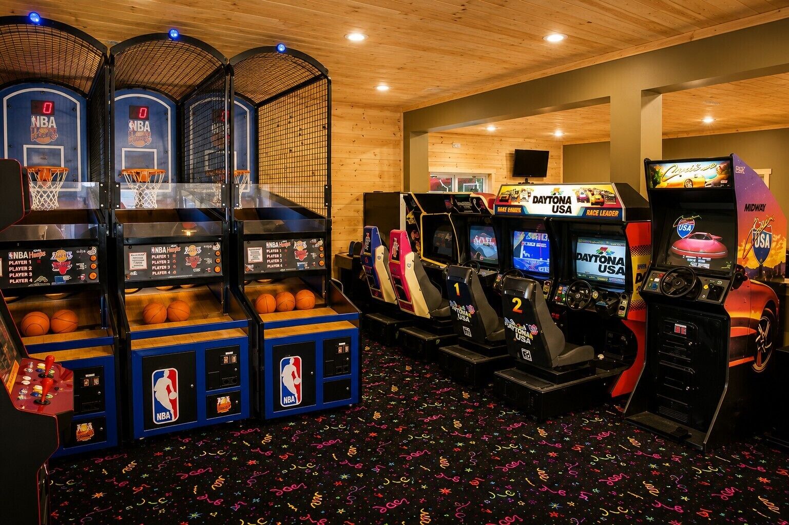 An indoor arcade with basketball and racing game machines, wooden walls, and a patterned floor.