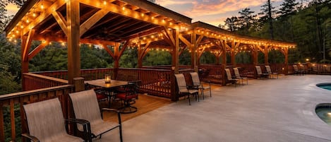 A covered outdoor patio with wooden furniture and string lights.