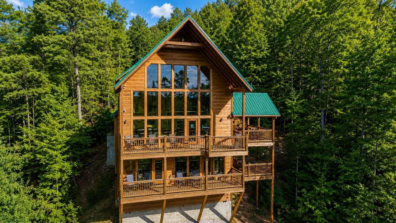 A two-story wooden cabin with balconies, surrounded by dense forest.