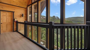 Un intérieur en bois, avec de grandes fenêtres, une porte en bois et une vue sur un paysage verdoyant.