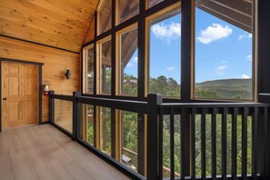 A wooden interior with large windows, a wooden door, and a view of a green landscape. - Near Dollywood + Resort Amenities Included (Pigeon Forge)