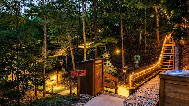 A wooden deck with a hot tub, a sign indicating 'PUTT-PUTT HIGH POINTS,' and a wooden structure with a ladder.