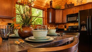 A wooden interior with a kitchen counter, dining table, and cabinets. - Cabin + FREE Resort Amenities | Pigeon Forge (Pigeon Forge)
