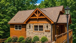 Un chalet doté d’une façade en pierre, de boiseries et d’un porche abrité.