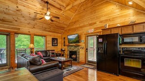 L’intérieur d’une cabane comprend une cheminée, un téléviseur, un réfrigérateur et un coin repas.