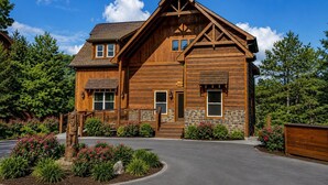 Une cabane en bois avec des fondations en pierre, un porche à l’avant et une allée.