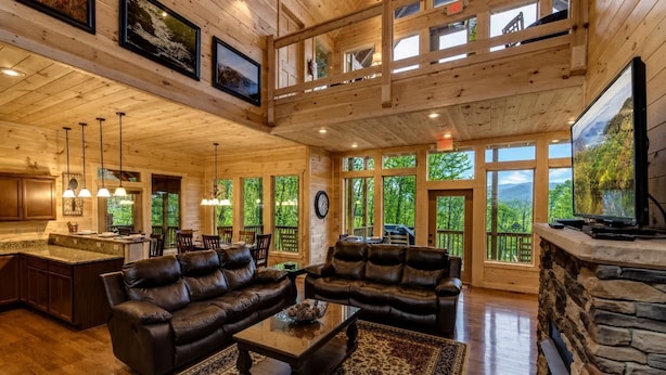 A spacious living area with leather sofas, a coffee table, and a stone fireplace.
