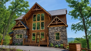 A log cabin with a stone facade, multiple windows, and a porch.