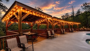 A covered outdoor patio with wooden furniture and string lights.