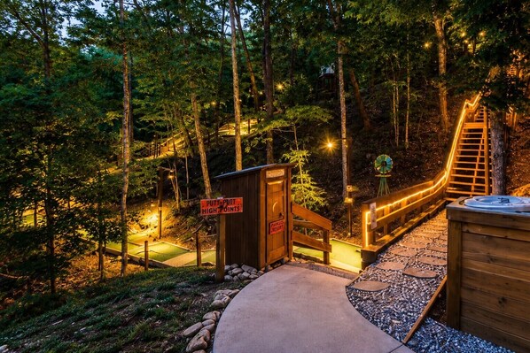 A wooden deck with a hot tub, a sign indicating a park and resort, and a wooden staircase leading up. - Cabin + FREE Resort Amenities | Pigeon Forge (Pigeon Forge)