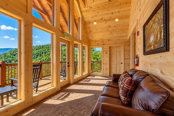 Une cabane en bois avec un balcon, un canapé en cuir et un tableau accroché au mur.