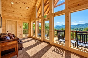 A wooden cabin interior with a large window overlooking a scenic mountain view.