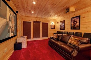 A cozy room with wooden walls, a red carpet, a leather sofa, and framed pictures on the walls.