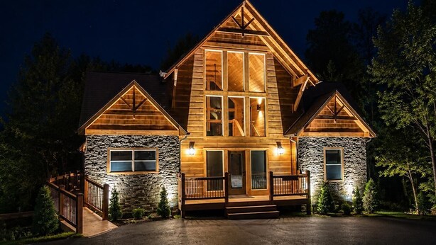 A large, two-story log cabin with a stone foundation, a front porch, and a driveway. - Cabin + FREE Resort Amenities | Pigeon Forge (Pigeon Forge)