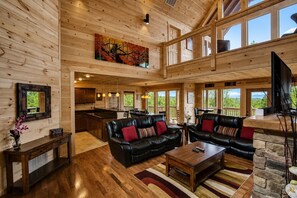 A spacious living area with a fireplace, a dining table, and a kitchen in the background.
