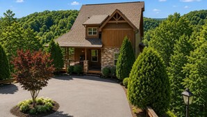 Une maison à deux étages avec une façade en pierre, un porche en bois et un garage.
