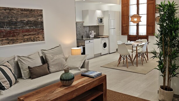 A modern living room with a wooden coffee table, a sofa, and a dining area with chairs and a table. - Mediterranean home (Palma)