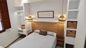 A modern bedroom with a large bed, a ceiling fan, wall-mounted shelves, and a framed picture above the bed. - Mediterranean home (Palma)